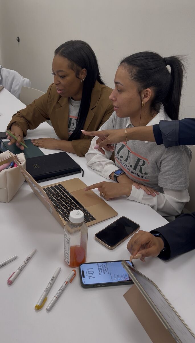 Two women working closely together at a laptop, one pointing at the screen while mentoring